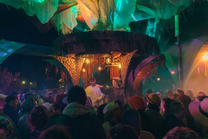 Crowd gathered beneath green-lit canopy at night